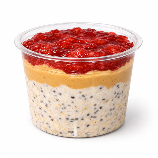 Peanut butter and jelly overnight oats in a clear cup on a white background